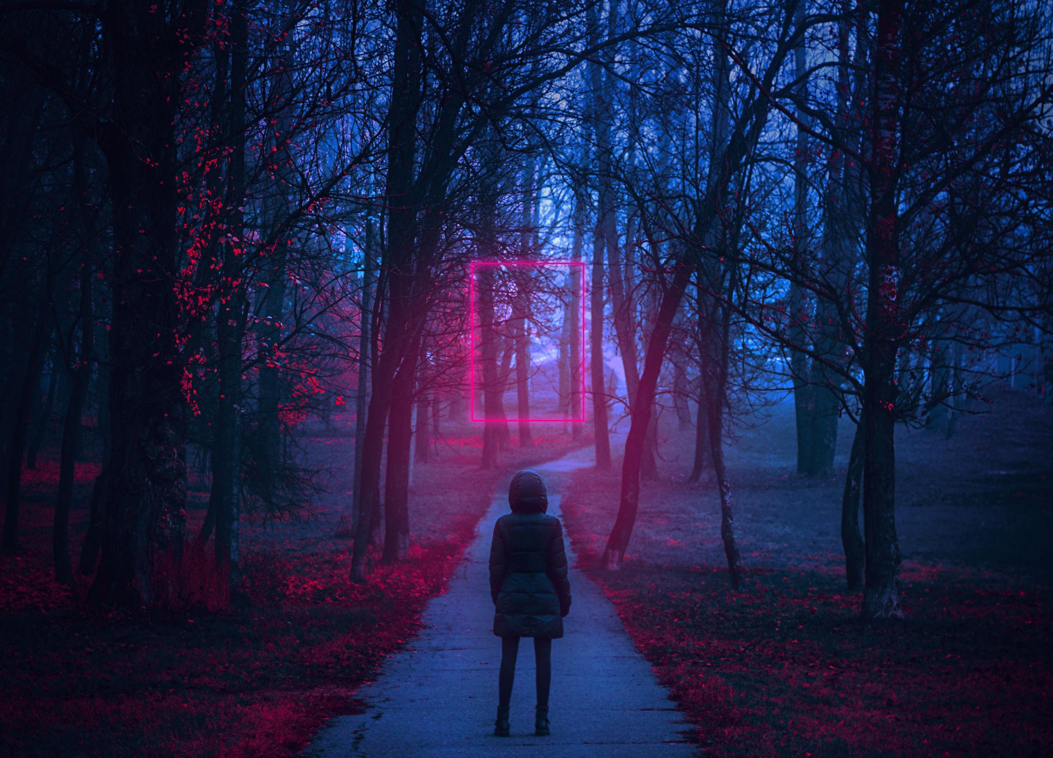 Silhouette d’une jeune fille face à un portail lumineux rouge et bleu